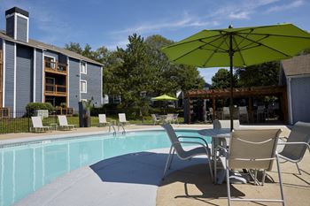 A pool area with chairs and an umbrella.